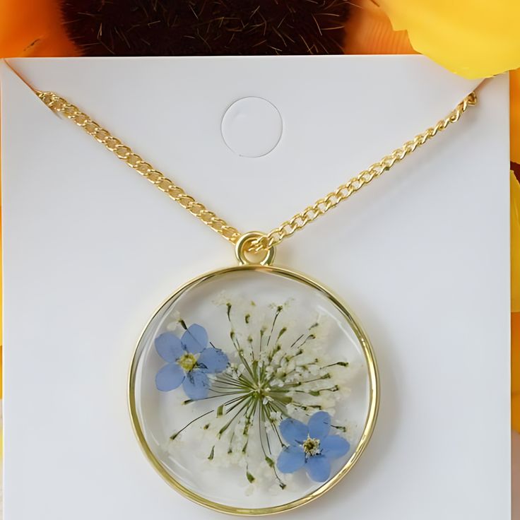 Our gorgeous Crystal Epoxy Resin Floral Neckless will add a touch of elegance to your jewelry collection. This one-of-a-kind creation, which has actual flowers preserved in crystal-clear resin, beautifully depicts the beauty of nature. The pendant is the ideal addition to any ensemble because of its vivid flower pattern, which adds a touch of elegance and uniqueness. Nature-Inspired Design: Every pendant is made by hand using actual flowers, guaranteeing a unique creation that honors the splendor of the natural world. Superior Quality: Constructed from premium epoxy resin, the pendant is lightweight and strong, making it comfortable to wear all day. Standard Chain Length: The pendant's 20-inch chain beautifully matches the pendant's style. Customizable Options: To make your pendant unique, Nature-inspired Resin Jewelry, Unique Flower-shaped Resin Jewelry, Unique Round Necklaces With Pressed Flowers, Unique Resin Flower Jewelry, Unique Pressed Flower Necklace, Unique Pressed Flower Jewelry, White Flower Shaped Glass Jewelry, Resin Flower Jewelry With Flower Charm, Flower Shaped Resin Jewelry For Gifts