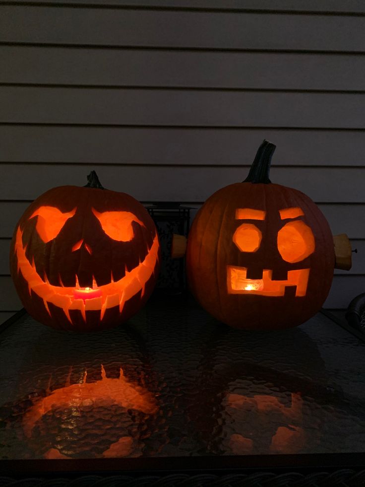 two carved pumpkins sitting on top of a table