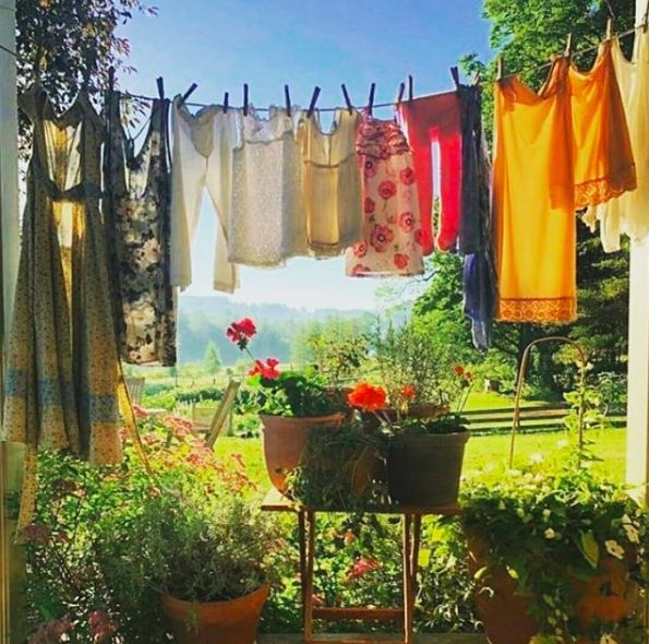 clothes hanging out to dry in the sun on a line with potted plants and flowers