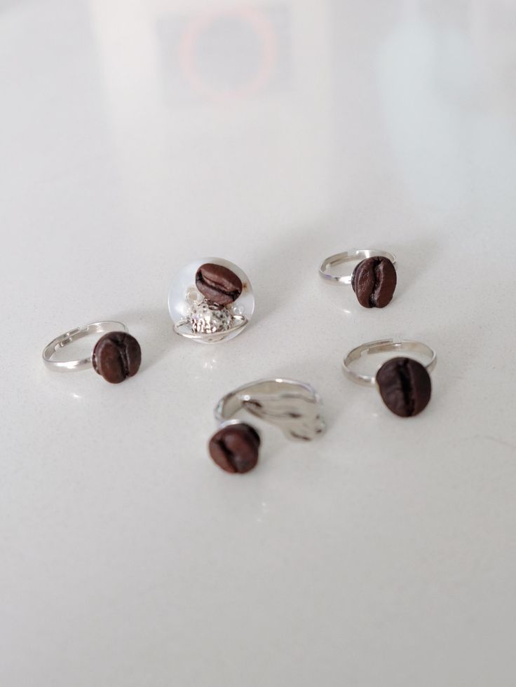 five rings with coffee beans on them sitting on a white counter top next to each other