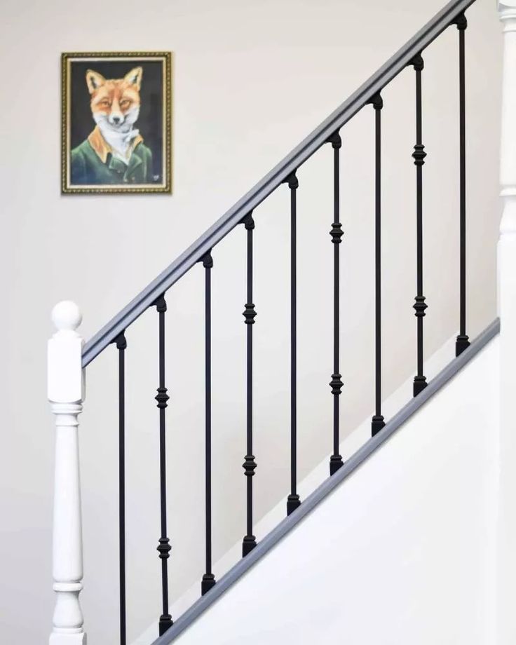 a dog is sitting on the stairs in front of a framed painting by a stair railing