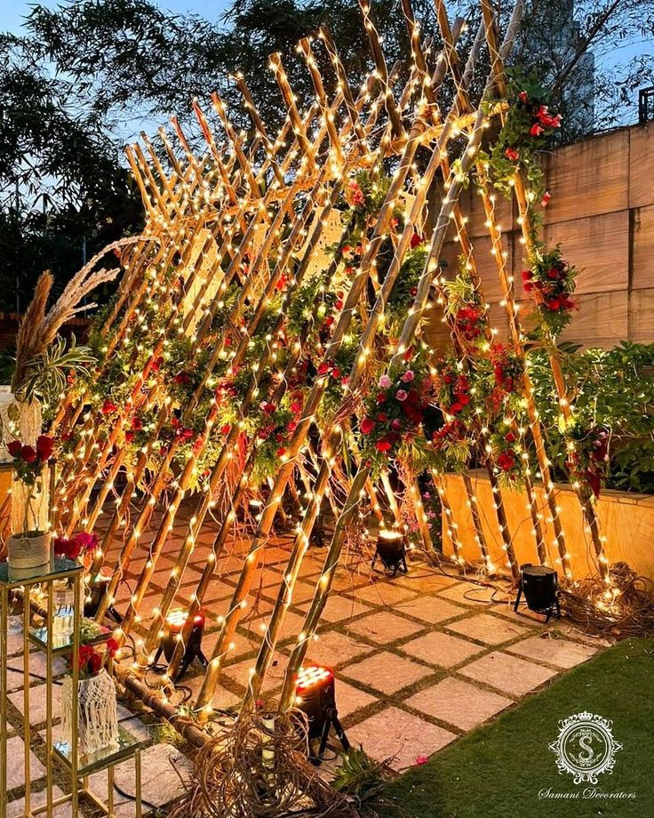 a wooden structure with christmas lights on it in the middle of a garden at night