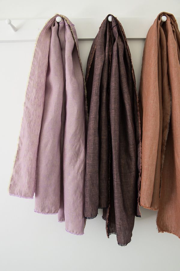 three scarves hanging on the wall in different colors and patterns, one is brown, one is pink