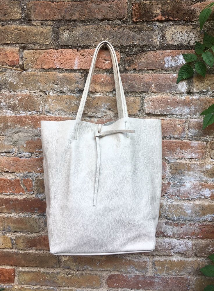 Large tote leather bag in a very light BEIGE shade. Broken white shopper bag natural GENUINE leather. Large enough for books or a laptop, tablet, cosmetics bag etc. Creamy white Leather shopper. The inside of the bag is not lined (although properly finished!) . We added a small leather pouch on the inner part of the bag . The bag can be closed by 2 leather straps attached to each side. Excellent quality soft but strong genuine leather. The color of the bag in this listing is a very light beige c Bag For Books, Tote Leather Bag, Suede Tote Bag, Slouch Bags, Tablet Bag, Small Coin Purse, White Tote Bag, Broken White, White Tote