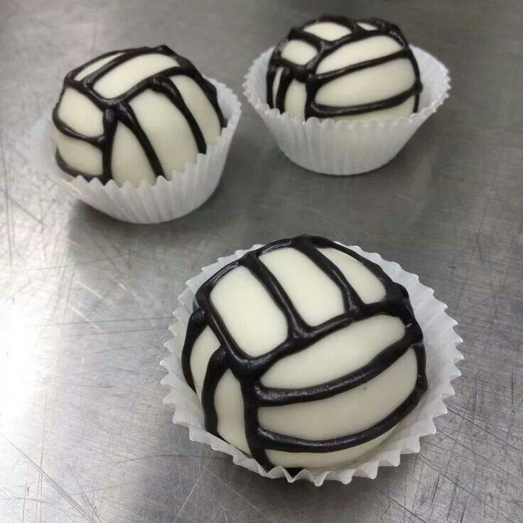 four white and black desserts sitting on top of a silver table with one chocolate covered in icing