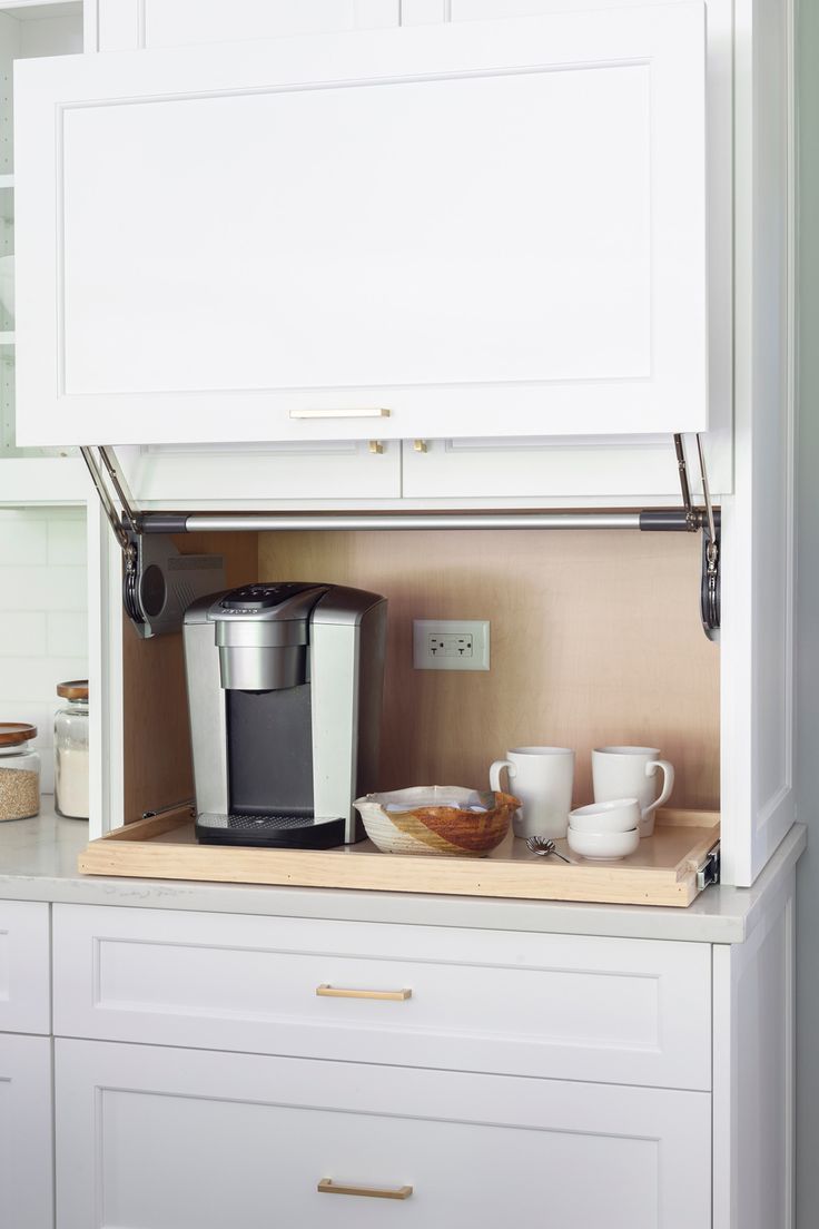 the coffee maker is sitting on top of the counter in the kitchen with white cabinets