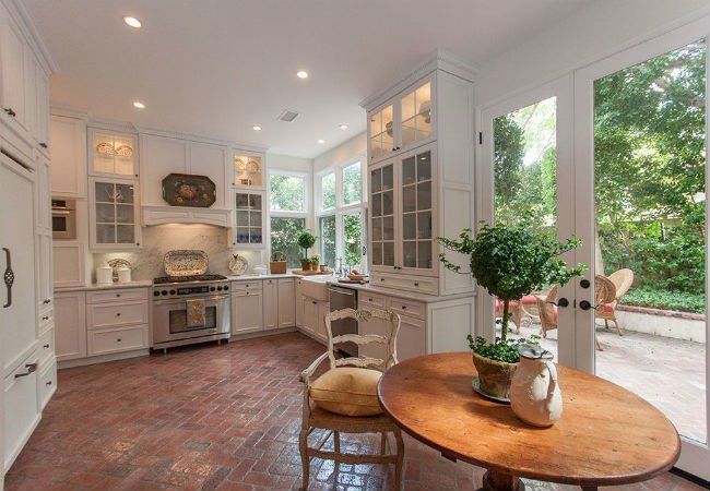 a kitchen with white cabinets and brick flooring