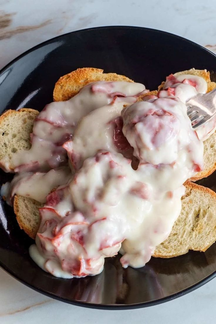 a black plate topped with meat covered in gravy