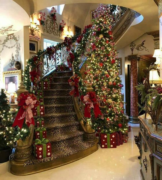 christmas trees and presents are on display at the bottom of stairs in this large foyer