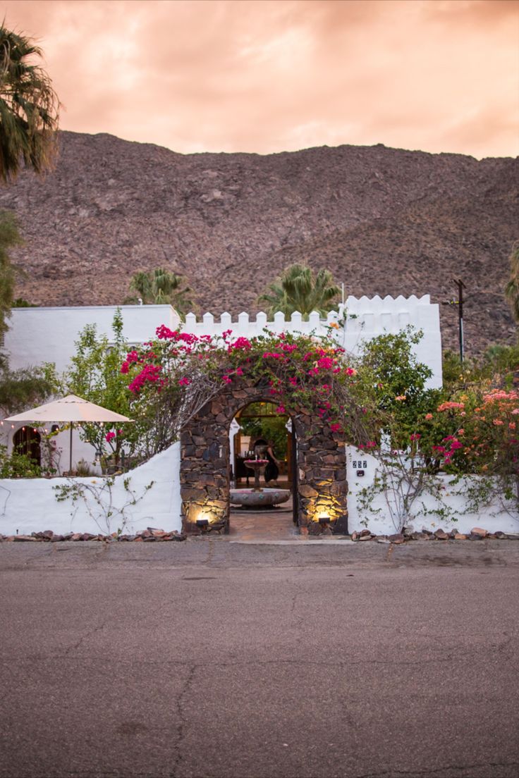 the entrance to an adobe style house with flowers growing on it