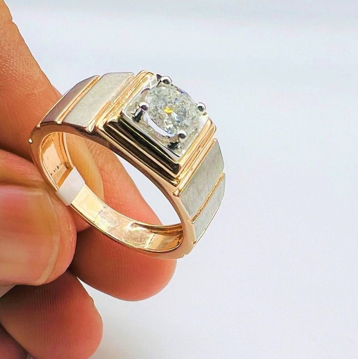 a hand holding a gold and silver ring with a diamond in it's center