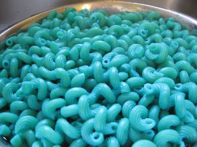 a bowl filled with lots of blue macaroni and cheese in green icing