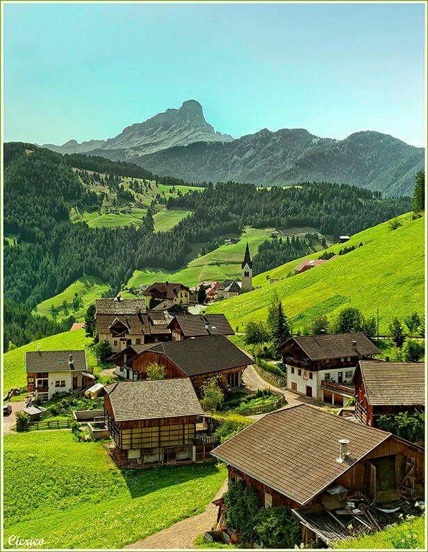 a village in the mountains surrounded by green grass