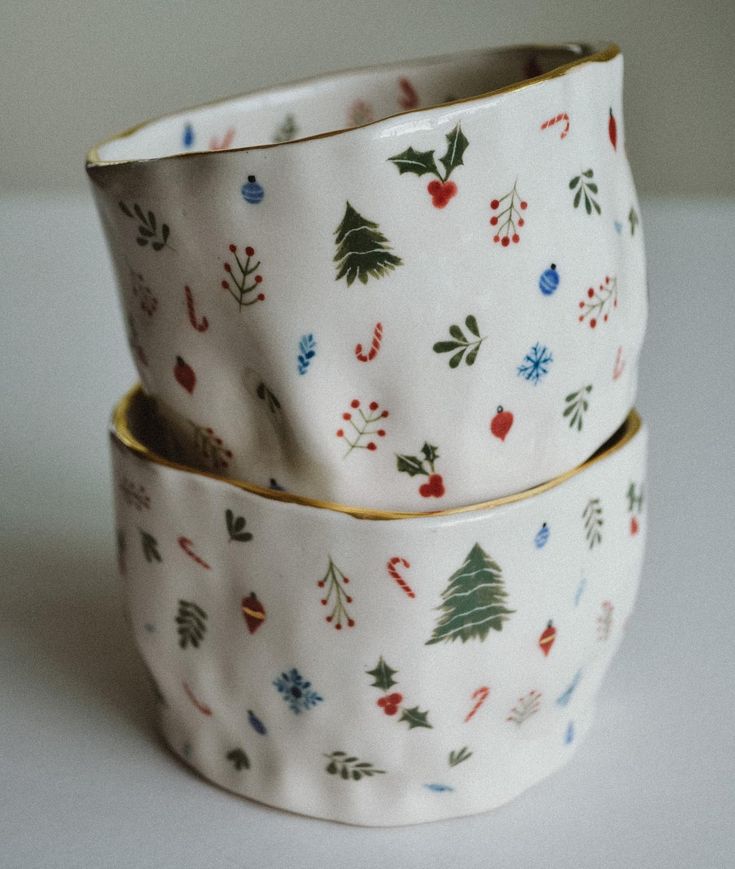 two bowls are stacked on top of each other, decorated with christmas trees and berries