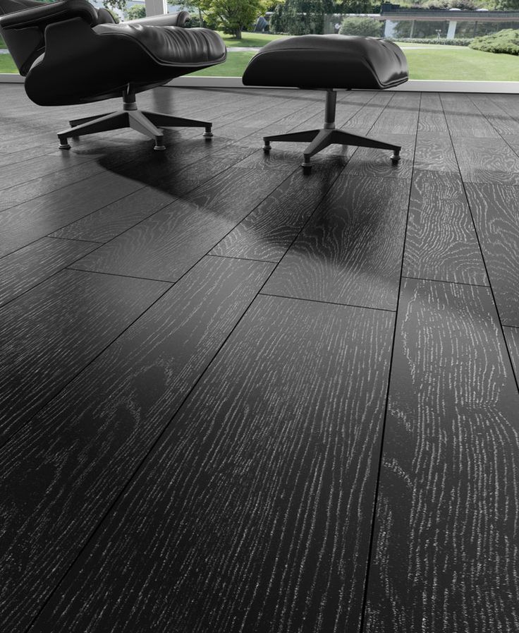 an eames lounge chair and ottoman on a wood floor in front of a large window