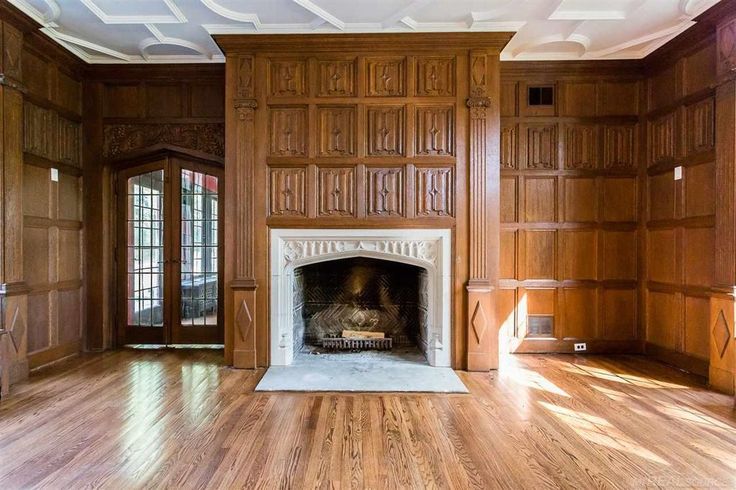 an empty living room with wood paneling and a fireplace