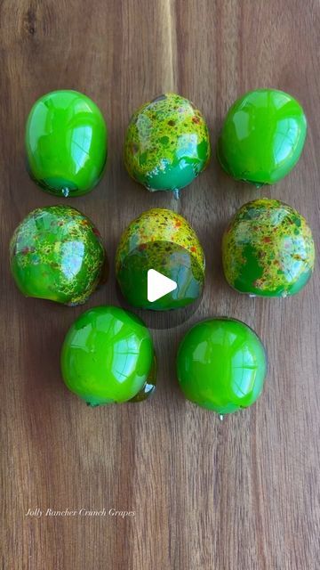 green and yellow marbles on a wooden table with a video play button in the middle