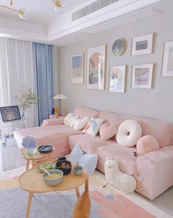 a living room with pink couches and pictures on the wall above it, while a dog is standing in front of the couch