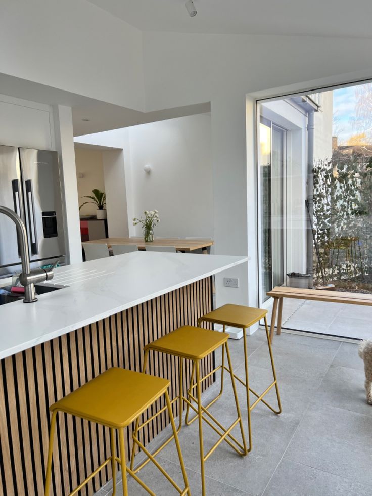 three stools are sitting at the bar in this modern kitchen with sliding glass doors