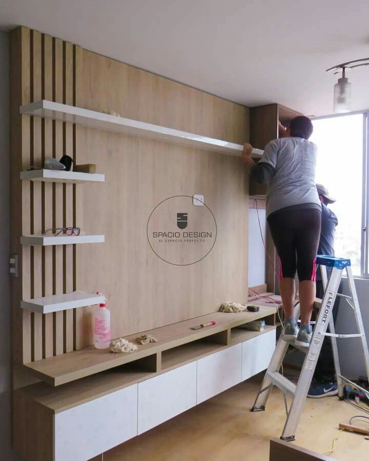 a man standing on a ladder in front of a wall mounted shelving unit with shelves