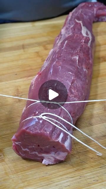 a piece of raw meat on a chopping board being cut into smaller pieces with an electric wire