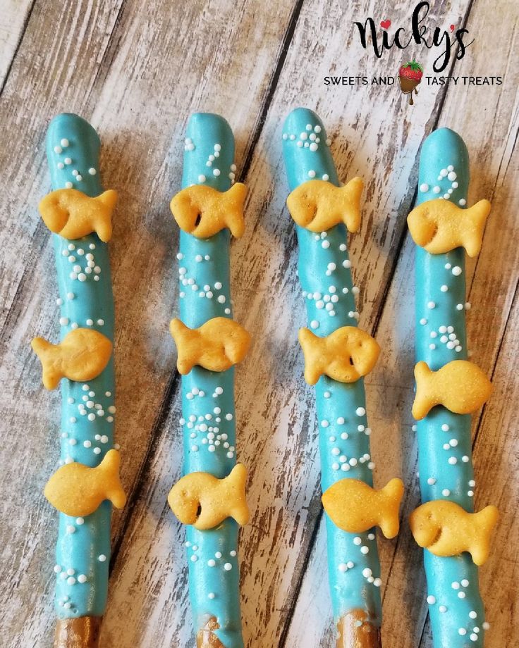 four blue and gold decorated toothpicks with fish on them, sitting on a wooden table