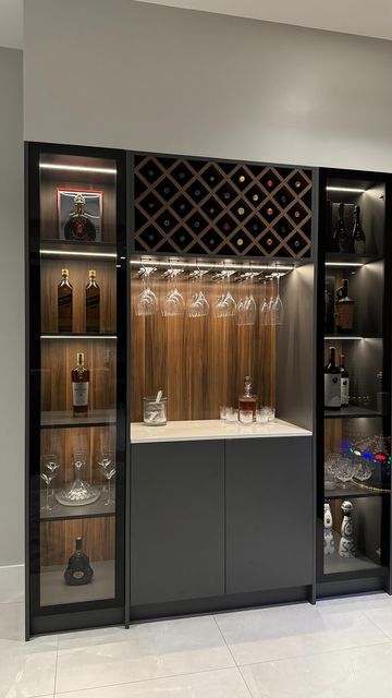 a wine cellar with many bottles and glasses in it's display case, along with other items on the shelves