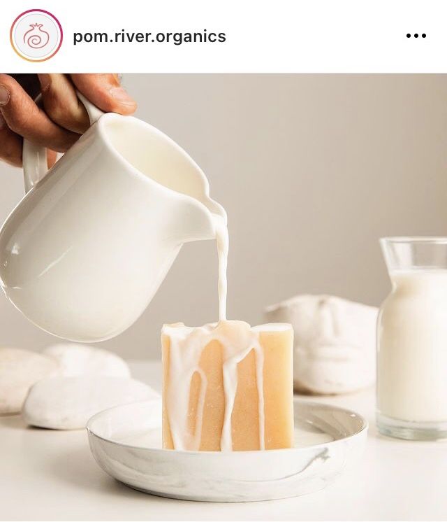 a person pouring milk into a cake on top of a white plate next to a cup