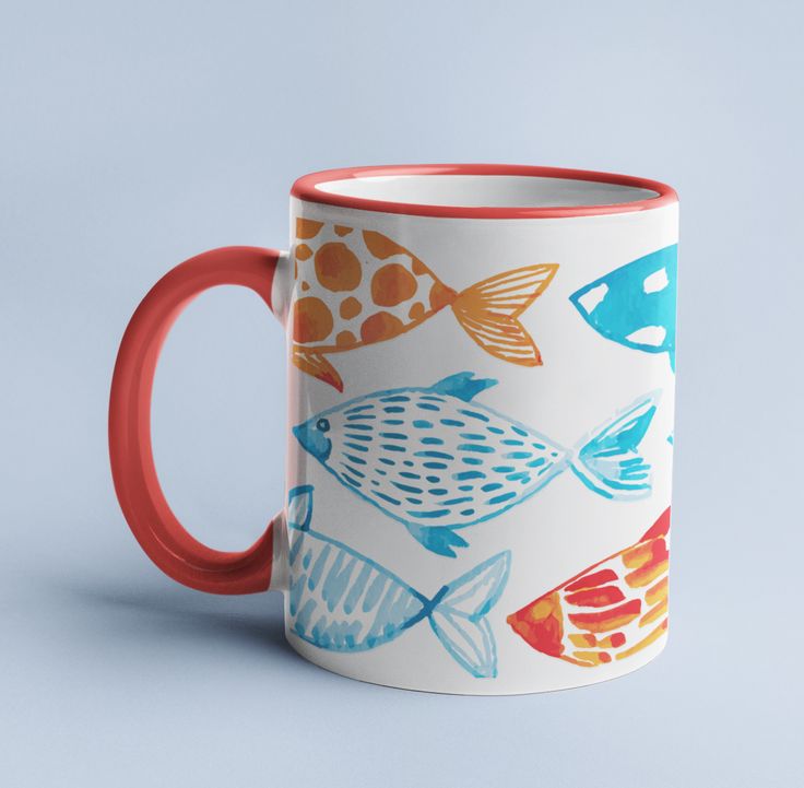 a colorful coffee mug with fish on it is sitting against a blue background and has an orange rim