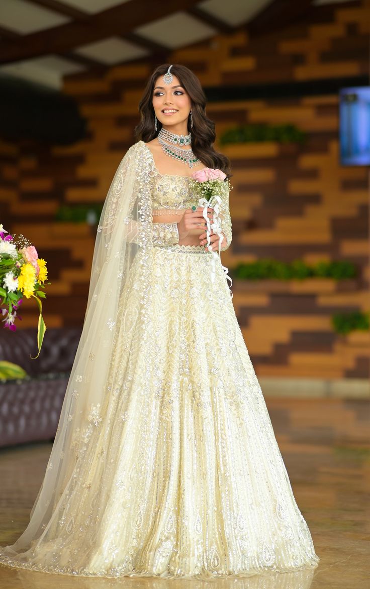 This regal ivory lehenga features all over sequin, cutdana, crystal and pearl embroidery paired with a full sleeves square neck blouse. The embroidered dupatta is crafted in net.DELIVERY TIMEPlease allow 8-12 weeks for your outfit to arrive.FABRIC DETAILSNetProfessional cleaning only. Ivory Lehenga, Engagement Looks, Bridal Crop Top, Christian Bridal Saree, Kurta Lehenga, Square Neck Blouse, Lehenga Jewellery, White Lehenga, Engagement Hairstyles