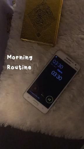 a cell phone sitting on top of a white rug next to a gold box and a book