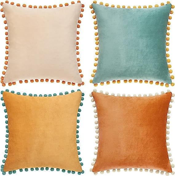 four different colored pillows with pom - poms on them