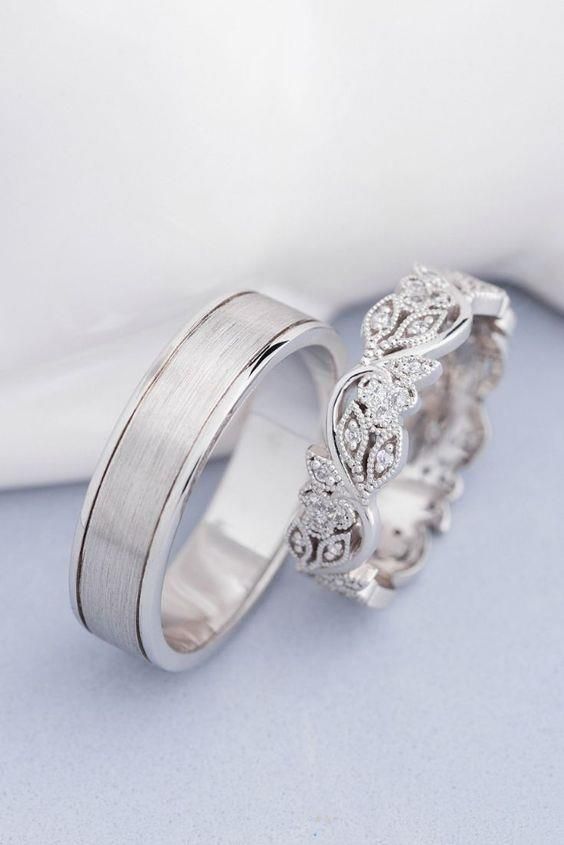 two white gold wedding rings with diamonds on top of each other in front of a white background