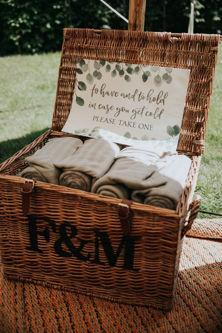 a wicker basket filled with folded towels on top of a blanket covered floor next to a sign