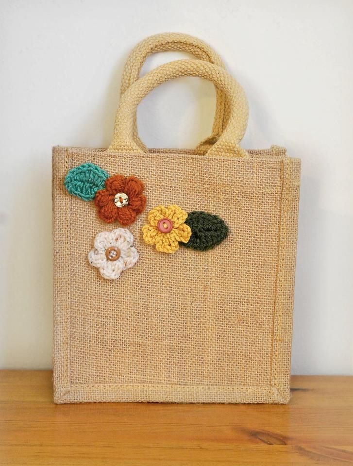 a jute bag with flowers on it sitting on top of a wooden floor next to a wall