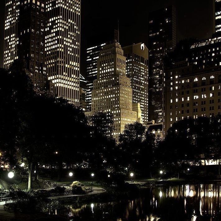 the city is lit up at night with lights reflecting in the water and skyscrapers