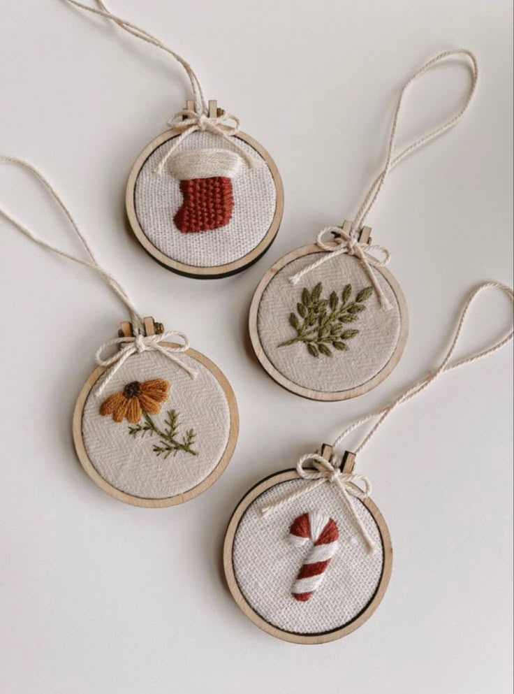 three cross stitch christmas ornaments hanging from twine