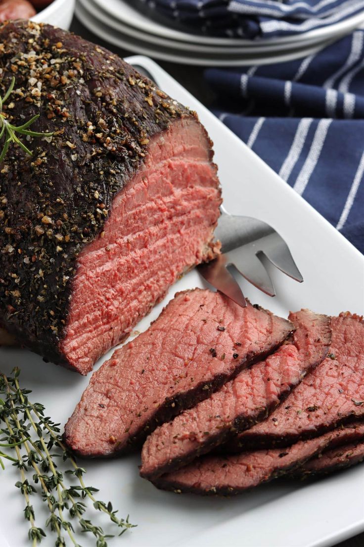 a piece of meat on a white plate with a knife and fork next to it