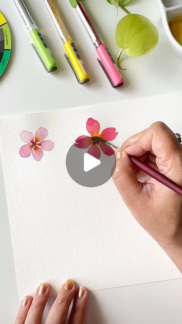 someone is painting flowers with watercolors on paper