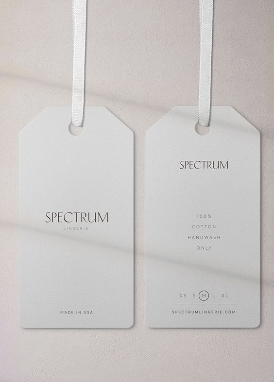 two white tags hanging on a wall with the words spectrum printed on them