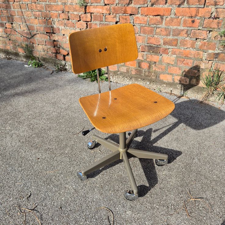 an office chair sitting on top of a cement floor next to a red brick wall