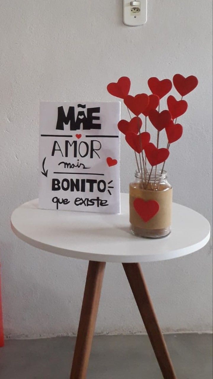 a small vase with some red hearts in it and a sign that says mae amr main bonito que exite