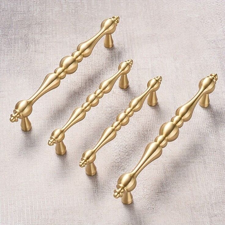 four gold colored handles and knobs on a white cloth