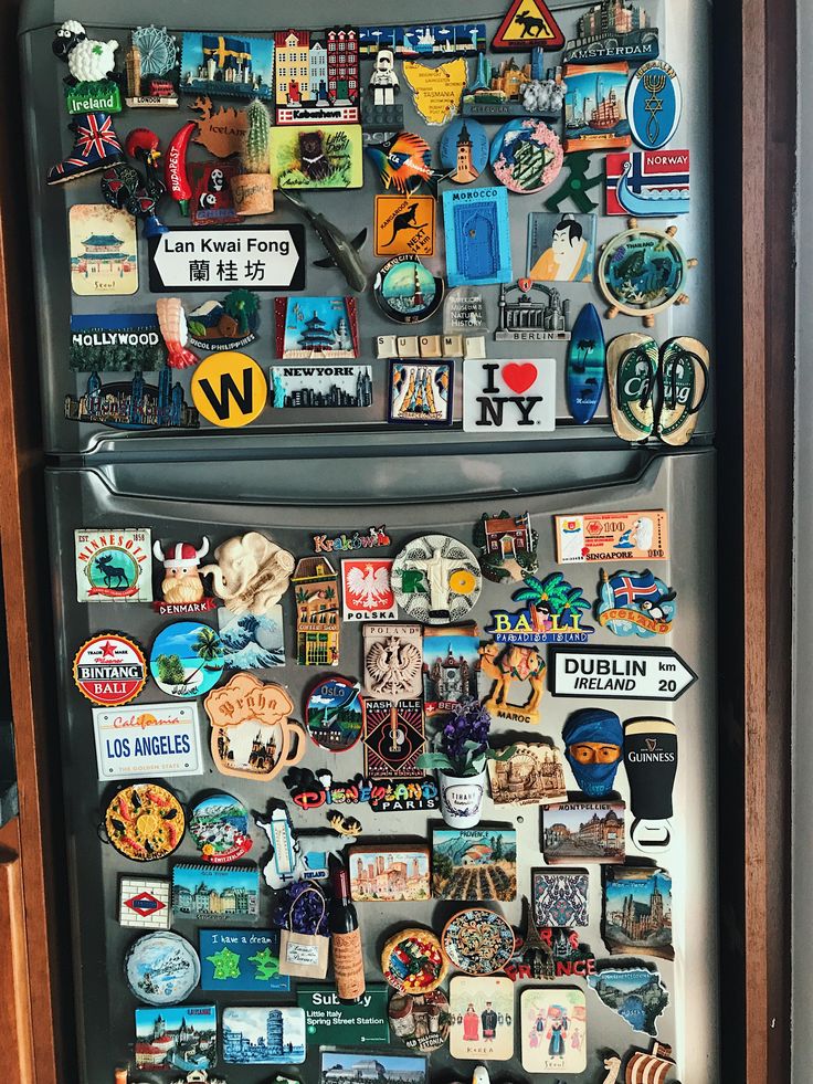 a refrigerator covered in lots of magnets and stickers on it's side