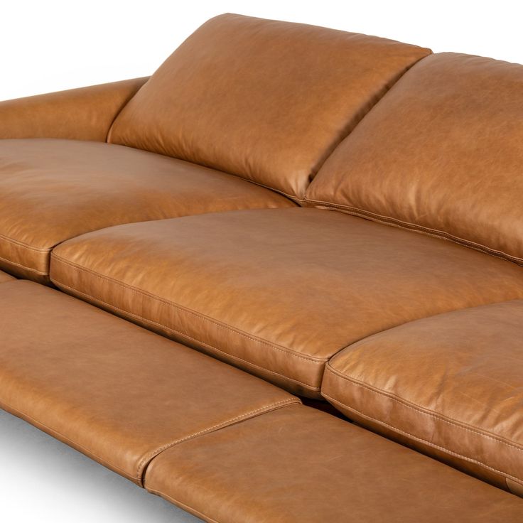 a brown leather couch with two pillows on it's back end and the arms folded down