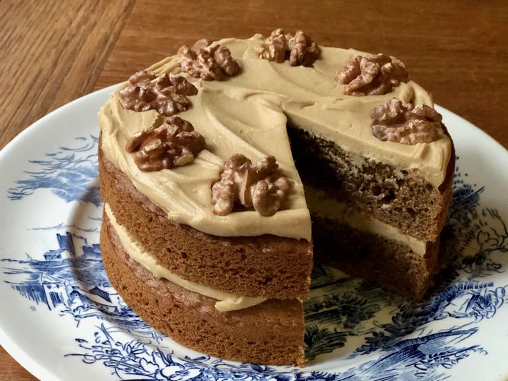 a cake with walnuts and frosting on a blue and white plate, cut in half