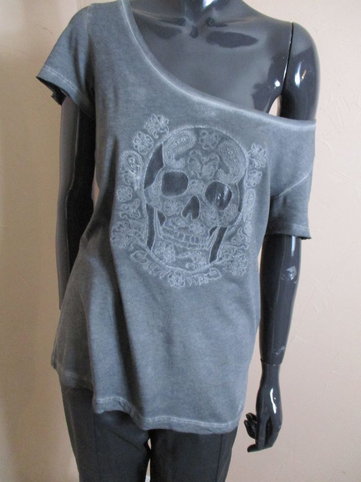 Vintage oversized tee shirt in distressed grey with a round neck and short sleeves.  The front has a skull with fowers surrounding it,  the back has small decorative buttons  down the back. Dimensions: Size: M Bust: 38 Inches. Length: 24 Inches. Made in France cotton Gray Distressed Grunge T-shirt, Punk Skull Print T-shirt For Summer, Edgy Skull Print Relaxed Fit T-shirt, Bohemian Cotton T-shirt For Streetwear, Cotton Grunge T-shirt With Skull Print, Punk Skull T-shirt For Summer, Summer Punk T-shirt With Skull Design, Summer Punk Skull T-shirt, Edgy Skull Print T-shirt For Alternative Fashion