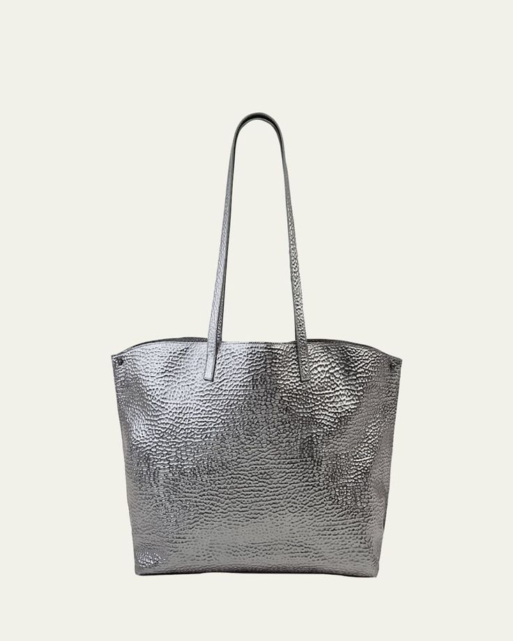 Akris metallic shoulder bag in hammered leather. Approx. 18.50"H x 12.20"W x 5.12"D; 11.42" drop. Two flat shoulder straps. Open top. Folded sides secure at turnlock front. Interior, two zip pockets. "AI" is imported. Luxury Grained Texture Shoulder Bag For Evening, Luxury Evening Shoulder Bag With Grained Texture, Luxury Grained Texture Evening Shoulder Bag, Elegant Metallic Shoulder Bag For Everyday Use, Metallic Elegant Shoulder Bag For Everyday, Elegant Everyday Metallic Shoulder Bag, Modern Formal Shoulder Bag With Grained Texture, Silver Leather Shoulder Bag With Magnetic Closure, Luxury Metallic Shoulder Bag With Palladium Hardware