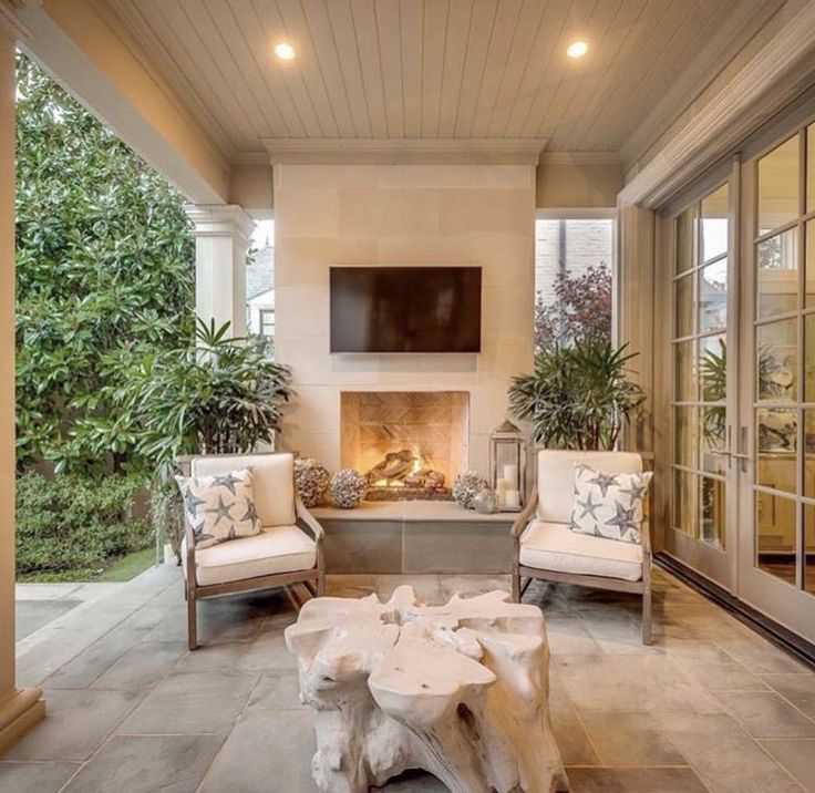 a living room filled with furniture and a fire place under a tv mounted on a wall