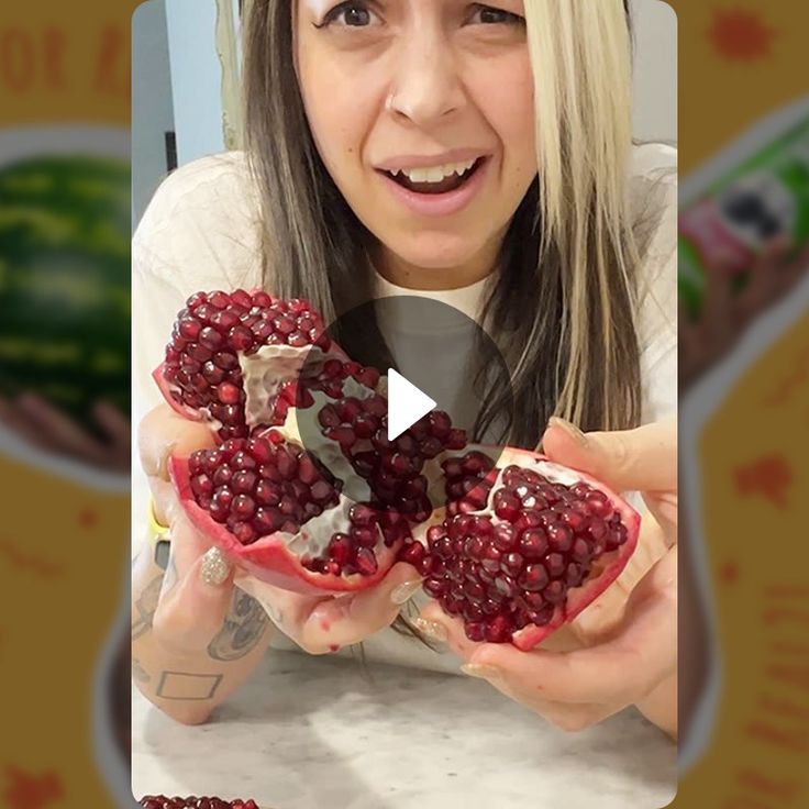 a woman holding up two pomegranates in front of her face and smiling at the camera